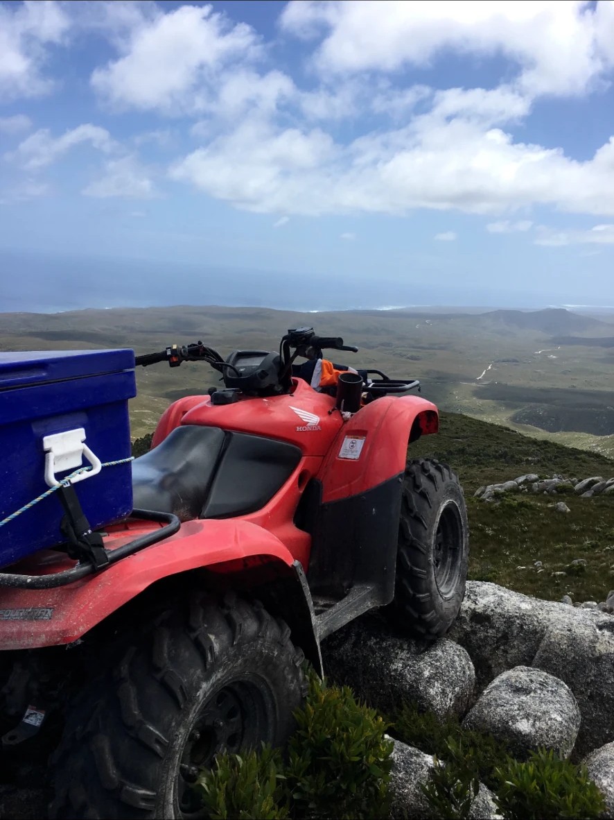 Honda quad bike with a Track & Wake drink holder fitted, parked on a rocky Tasmanian summit